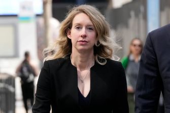 Elizabeth Holmes walking outside, appearing serious and focused.