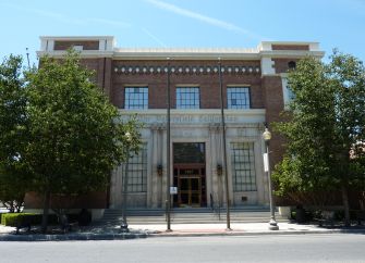 Historic building of The Bakersfield Californian newspaper, surrounded by trees under a clear sky.