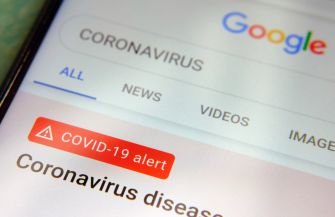 A smartphone screen displaying a Google search for "CORONAVIRUS" with a COVID-19 alert banner.