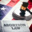 A book titled "Abortion Law" with a gavel resting on top, set against a backdrop of an American flag. A book titled "Abortion Law" with a gavel resting on top, set against a backdrop of an American flag.