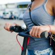 A person holding the handlebars of a motorized scooter. A person holding the handlebars of a motorized scooter.