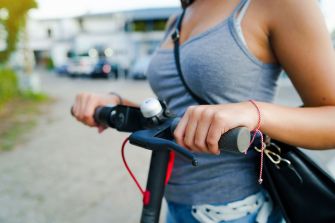 A person holding the handlebars of a motorized scooter.
