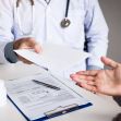 A medical professional handing a document to a patient during a consultation. A medical professional handing a document to a patient during a consultation.