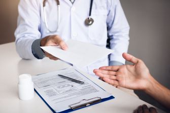 A medical professional handing a document to a patient during a consultation.