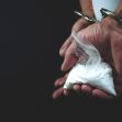 A hand holding a bag of white powdery substance while wearing handcuffs. A hand holding a bag of white powdery substance while wearing handcuffs.