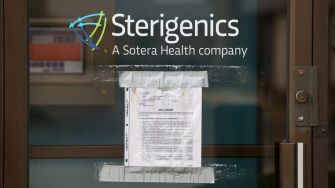Sign on the door of a Sterigenics facility indicating operational status, associated with Sotera Health.