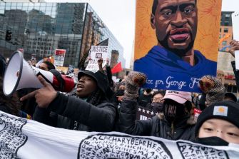 A group of protesters holding a banner and a portrait of George Floyd during a demonstration advocating for justice.