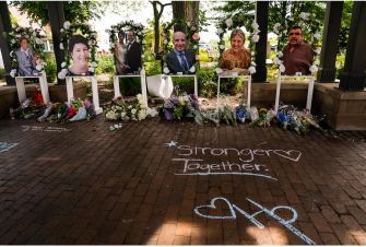 Memorial tribute for victims of the Highland Park shooting, featuring photographs and flowers, with the message "Stronger Together."