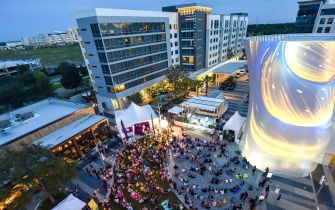 Aerial view of a vibrant gathering at Lake Nona Town Center, featuring outdoor dining and a large crowd enjoying the ambiance.