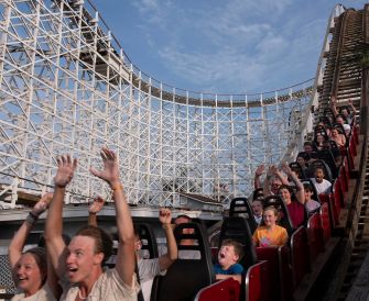 A wooden roller coaster in operation with riders experiencing excitement and thrill.