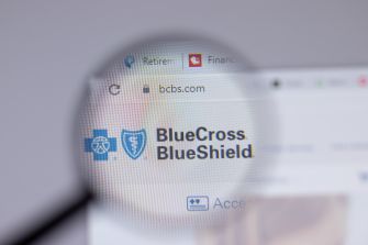 Logo of Blue Cross Blue Shield displayed on a website, viewed through a magnifying glass.