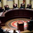 A courtroom scene featuring judges seated in a semicircular arrangement, discussing a legal case. A courtroom scene featuring judges seated in a semicircular arrangement, discussing a legal case.