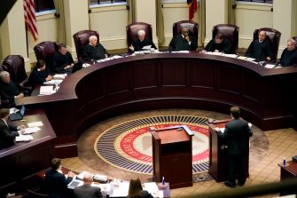 A courtroom scene featuring judges seated in a semicircular arrangement, discussing a legal case.