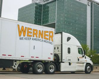 A Werner truck parked in front of a modern building.