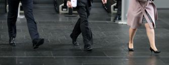 Footsteps of individuals in business attire walking on a tiled surface.