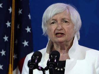 Janet Yellen delivering a speech, with the American flag in the background.