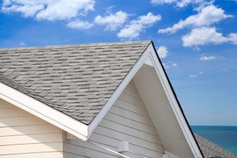 View of a sloped roof against a blue sky with scattered clouds.