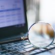 A magnifying glass on a laptop keyboard, symbolizing online searches for personal information. A magnifying glass on a laptop keyboard, symbolizing online searches for personal information.