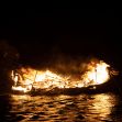 A burning funeral pyre on water, resembling traditional Viking funerals. A burning funeral pyre on water, resembling traditional Viking funerals.