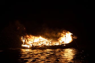 A burning funeral pyre on water, resembling traditional Viking funerals.