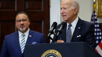 President Joe Biden delivering remarks on student loan forgiveness, with Education Secretary Miguel Cardona in the background.
