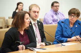A legislative hearing in Minnesota with three people seated at a table, discussing various issues.