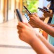 Group of children using smartphones while standing in a hallway. Group of children using smartphones while standing in a hallway.