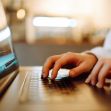A close-up of hands typing on a laptop keyboard. A close-up of hands typing on a laptop keyboard.