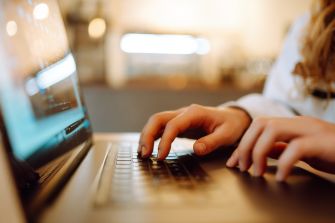 A close-up of hands typing on a laptop keyboard.