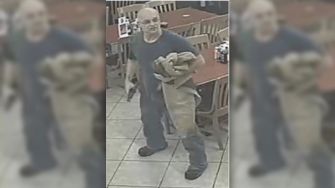 Surveillance image of a diner holding a gun inside a restaurant during a robbery.