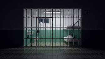 Image of a jail cell interior with two beds, visible bars, and minimal furnishings, highlighting the conditions faced by correctional officers.