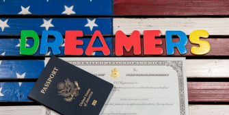 Colorful letters spelling "DREAMERS" next to a U.S. passport and a certificate on a background resembling the American flag.