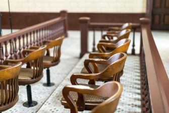 Empty wooden jury chairs in a courtroom setting.