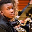 A Black teenager playing a musical instrument in a school band setting. A Black teenager playing a musical instrument in a school band setting.
