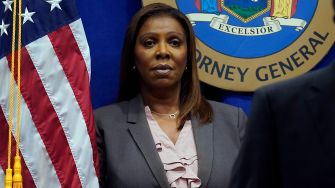 New York Attorney General Letitia James addressing the media, with the state seal and flag in the background.