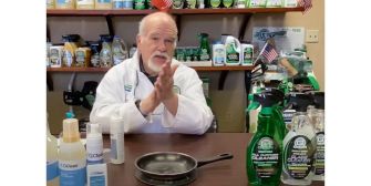 A chemist demonstrating cleaning products in a lab setting, surrounded by various bottles of disinfectants and cleaners.