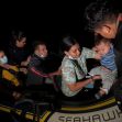 Migrants arriving by boat, including a woman holding a child, as they seek refuge. Migrants arriving by boat, including a woman holding a child, as they seek refuge.