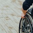 Person using a wheelchair on a pavement. Person using a wheelchair on a pavement.