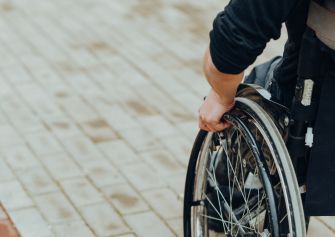 Person using a wheelchair on a pavement.