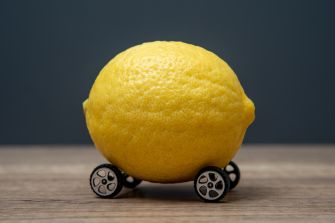 A lemon placed on toy car wheels, symbolizing the California lemon law and its controversies.