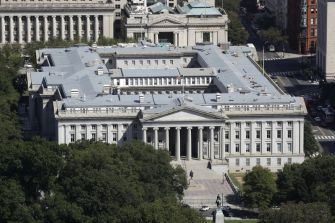Aerial view of the U.S. Department of the Treasury building, surrounded by trees and urban landscape.