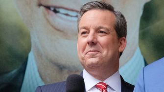 Former Fox News anchor Ed Henry speaking at an event, with a blurred background.