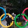 People wearing masks stand near the iconic Olympic rings in Tokyo, Japan. People wearing masks stand near the iconic Olympic rings in Tokyo, Japan.