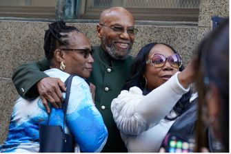 Muhammad Aziz poses for a photo with two women outside, celebrating his exoneration after wrongful conviction for the murder of Malcolm X.