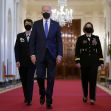 President Biden walking in the White House with two military officials, all wearing masks. President Biden walking in the White House with two military officials, all wearing masks.