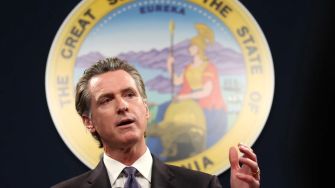 California Governor Gavin Newsom speaking at a podium with the state seal in the background.