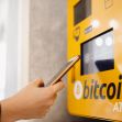 A person using a Bitcoin ATM with a smartphone. A person using a Bitcoin ATM with a smartphone.