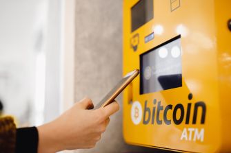 A person using a Bitcoin ATM with a smartphone.