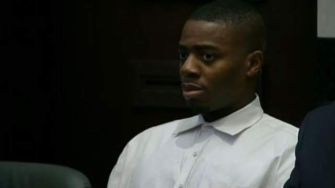 A man in a court setting, appearing serious and focused, wearing a white shirt.