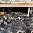 A burnt landscape under the freeway, showing damaged vehicles and debris from a pallet-fueled fire. A burnt landscape under the freeway, showing damaged vehicles and debris from a pallet-fueled fire.